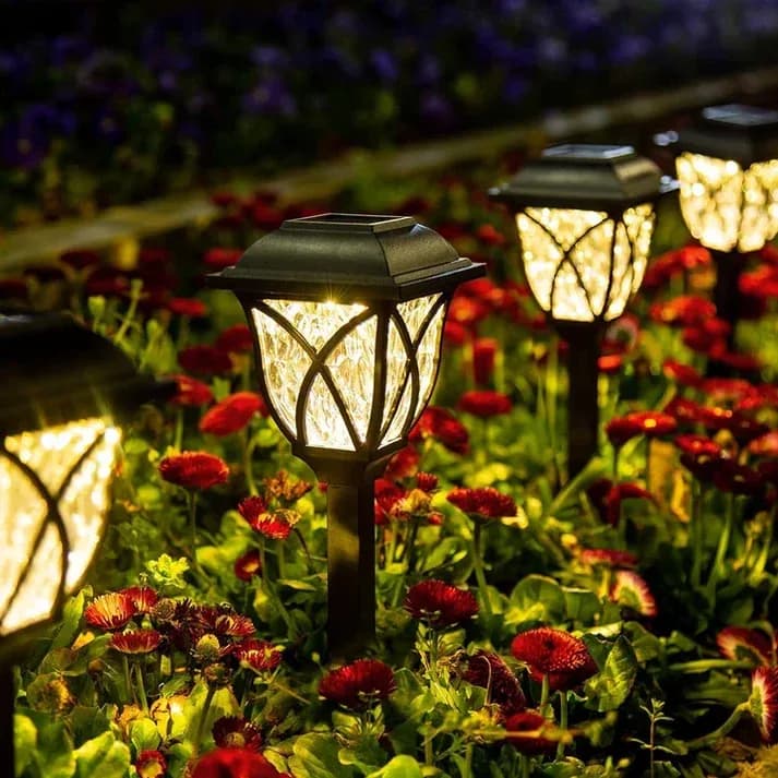 Dos faroles solares de 44 cm iluminando un cantero de flores de noche