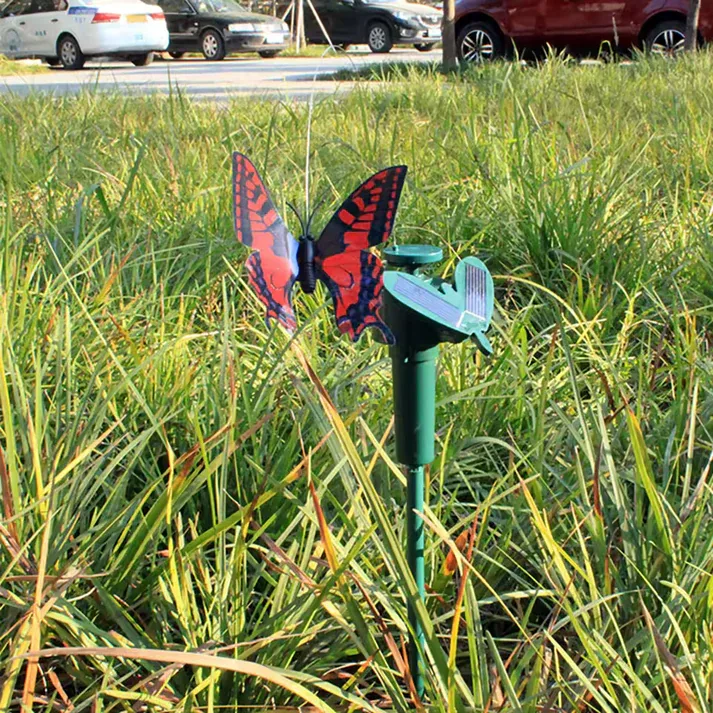 Mariposa solar sobre estaca moviendo las alas en el césped