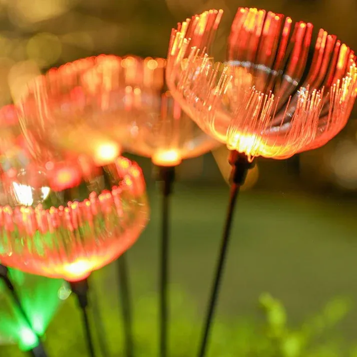 Flores medusa solares encendidas con colores en un jardín de noche